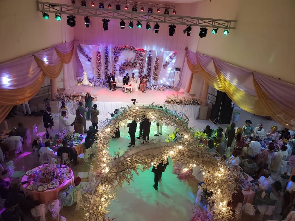 Main Auditorium during a wedding reception with stage, floral arch and lights