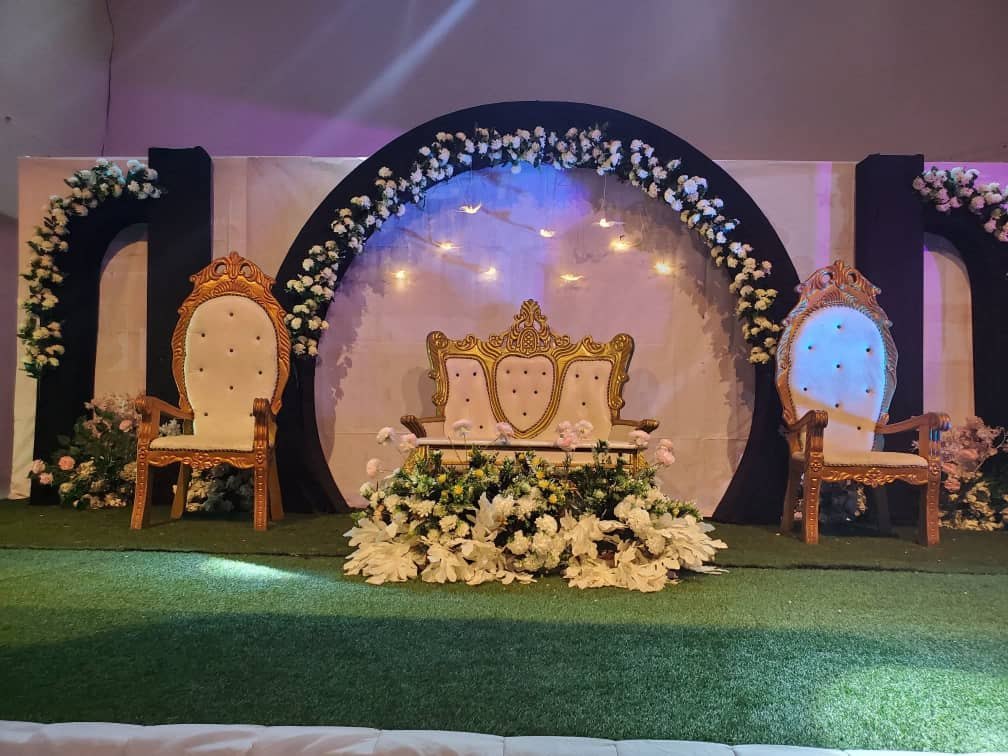 Stage with gold chairs and floral arch
